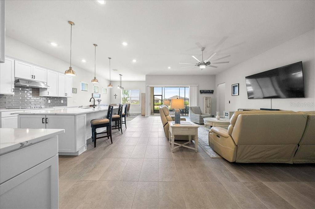 An open-concept kitchen and living area features white cabinetry, a large island, and tile flooring — 6015 SW 86TH CIRCLE, OCALA, FL