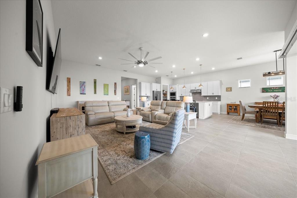 An open-concept living room and kitchen feature light tile flooring and white cabinetry — 6015 SW 86TH CIRCLE, OCALA, FL