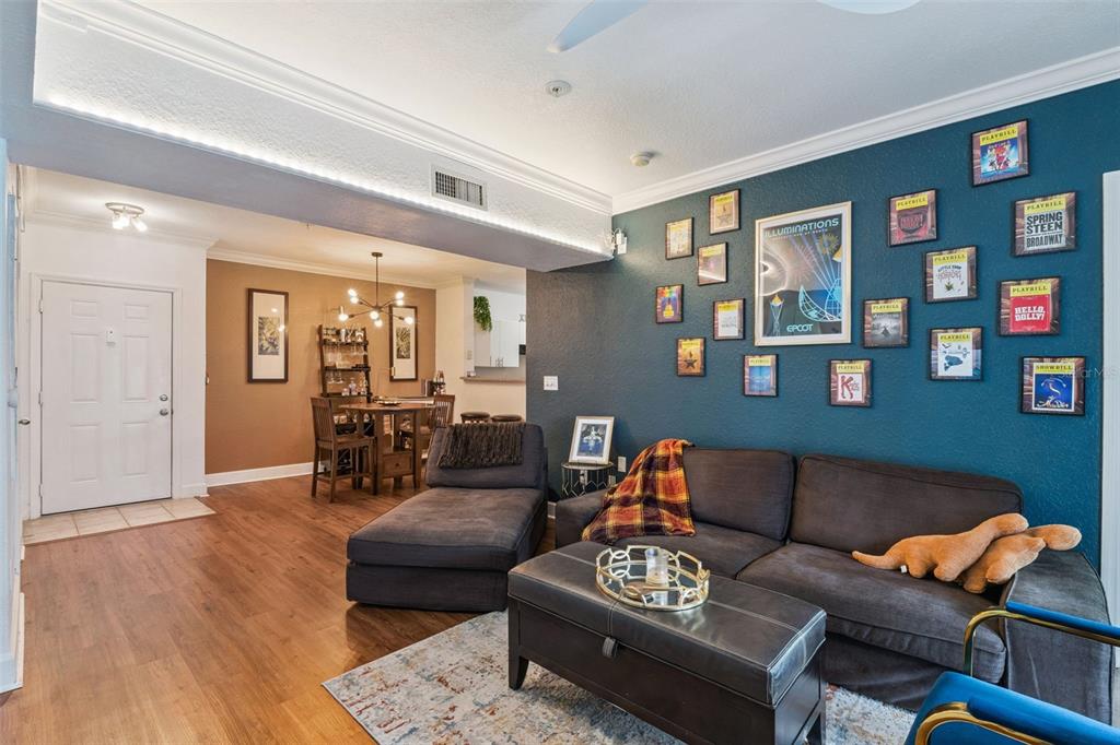 A living room with a dark blue accent wall, gallery of framed art, and wood flooring — 202 E SOUTH STREET UNIT 2039, ORLANDO, FL