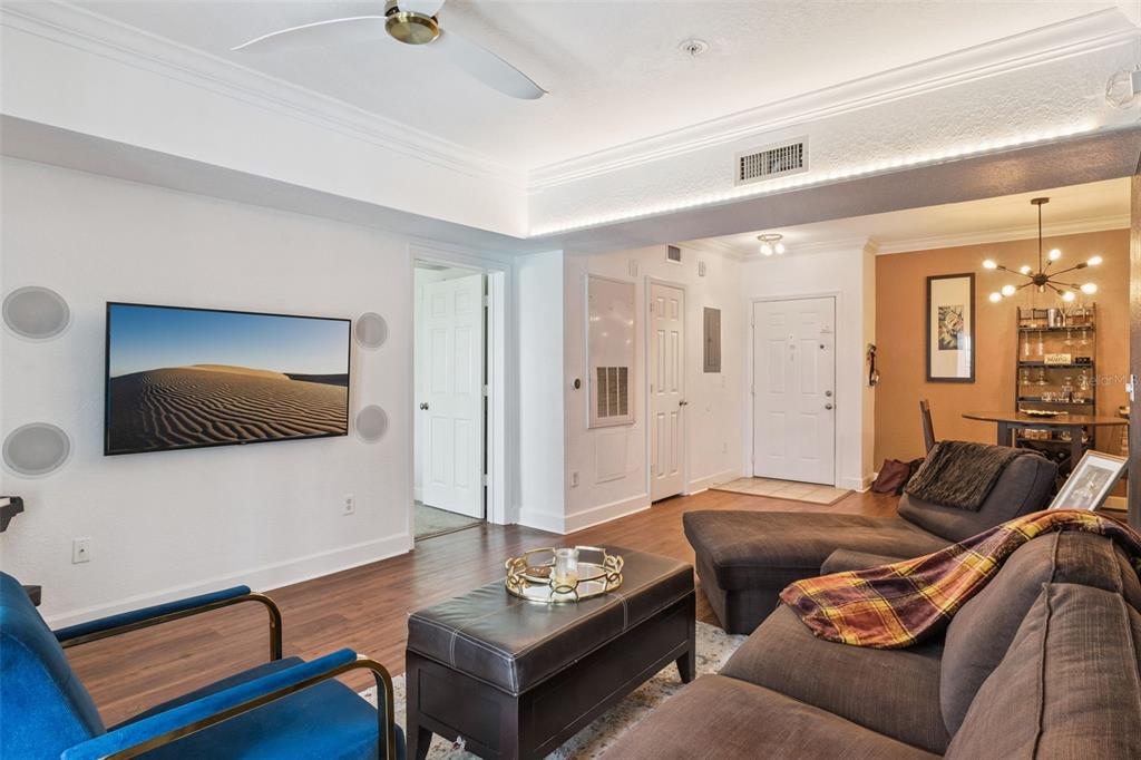 A living room features a wall-mounted television, dark sectional sofa, and an adjacent dining area — 202 E SOUTH STREET UNIT 2039, ORLANDO, FL