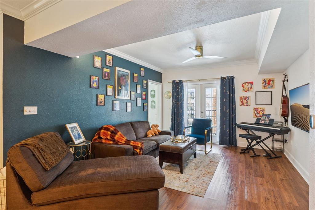 A living room features a dark teal accent wall, brown furniture, and a keyboard station — 202 E SOUTH STREET UNIT 2039, ORLANDO, FL