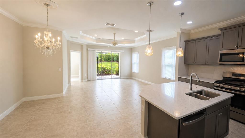 A kitchen with a center island and dining area featuring a chandelier and tray ceiling — 4520 DEEP CREEK TERRACE, PARRISH, FL