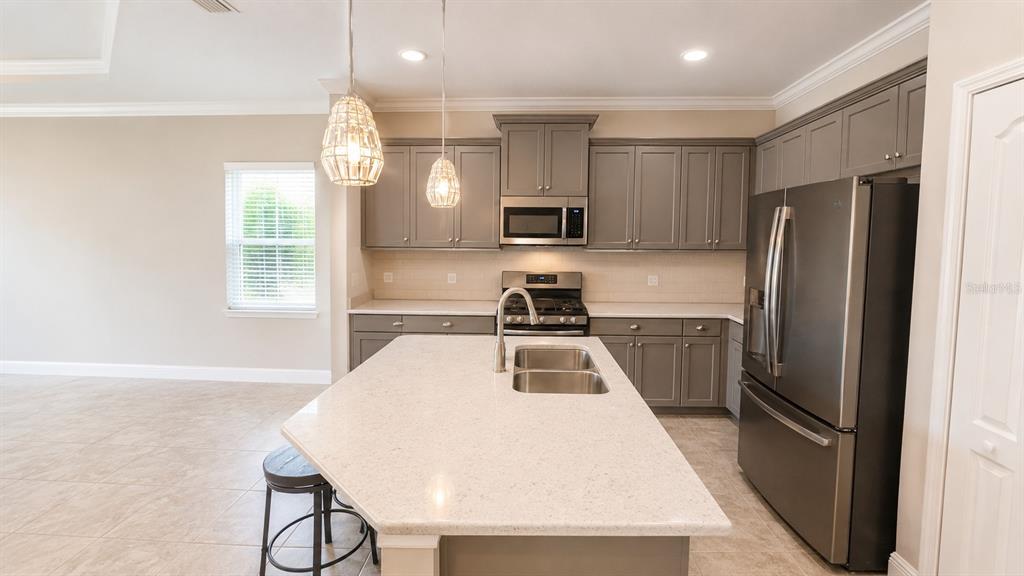 A kitchen features gray cabinets, stainless steel appliances, a quartz island, and tile flooring — 4520 DEEP CREEK TERRACE, PARRISH, FL
