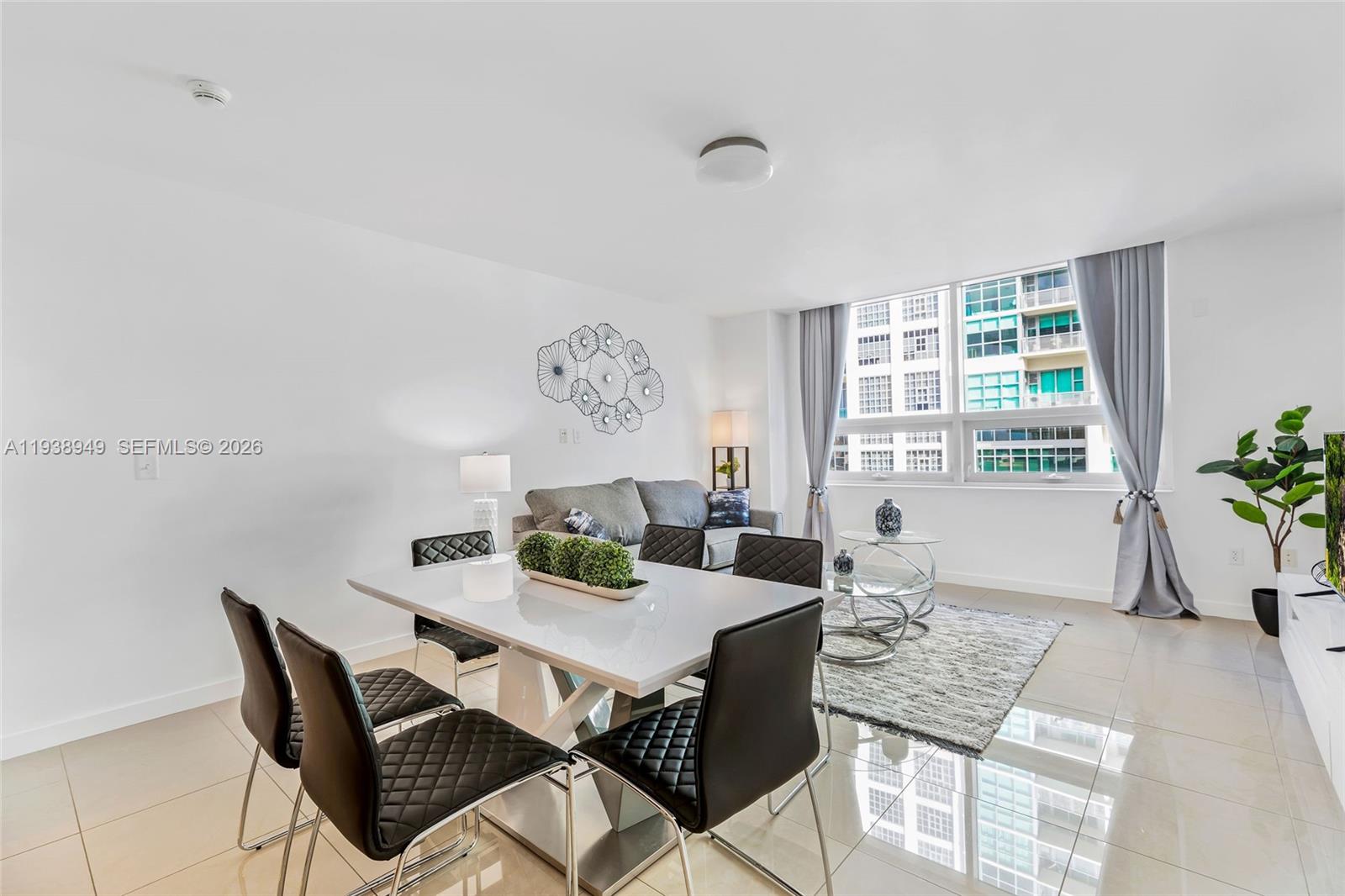 A modern living and dining area features white tile floors, a glass table, and gray furniture — 3250 NE 1st Ave # 603, Miami FL 33137, MIAMI, FL
