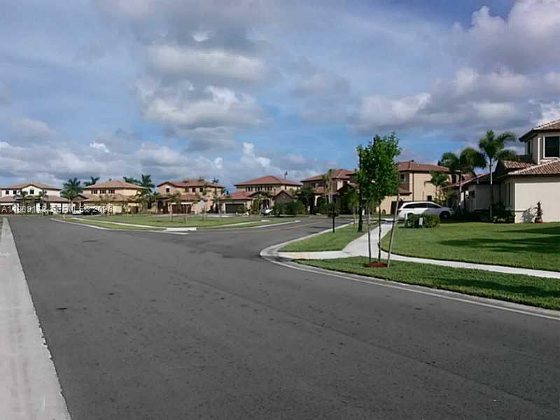 A residential street with houses, manicured lawns, and palm trees under a cloudy blue sky — 191 SE 35 TH AV., Homestead FL 33033, HOMESTEAD, FL