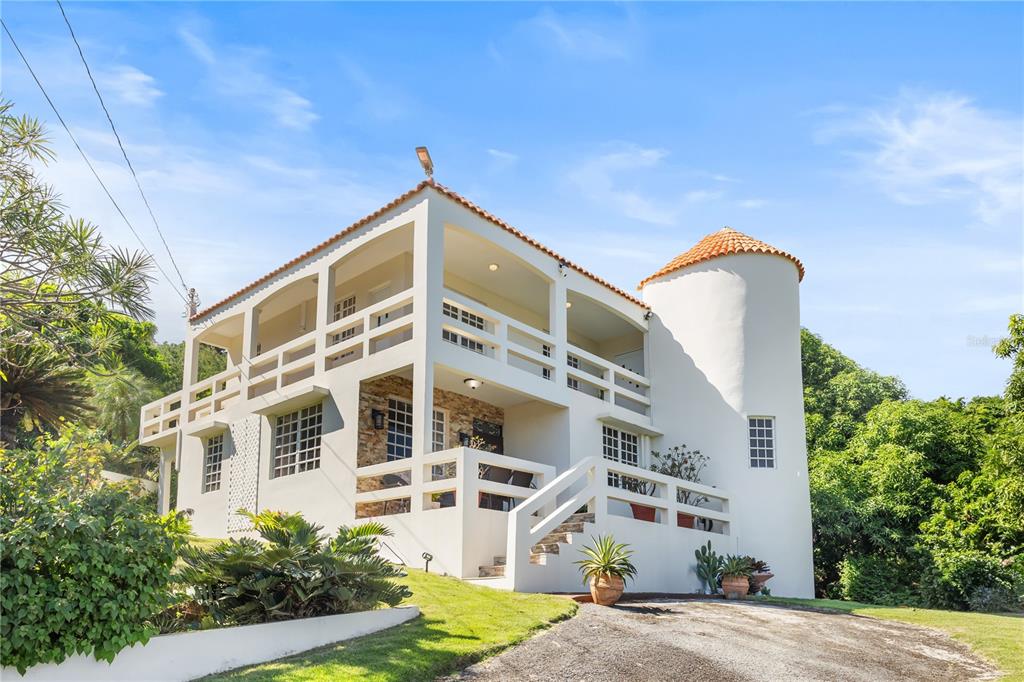 A two-story white house with a corner turret and wrap-around balconies sits on a lawn — 39 BO. CAMINO NUEVO, YABUCOA, PR