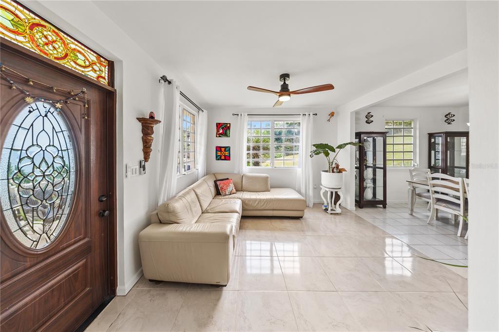 A living room with a beige sectional sofa, tile floors, and a stained-glass front door — 39 BO. CAMINO NUEVO, YABUCOA, PR