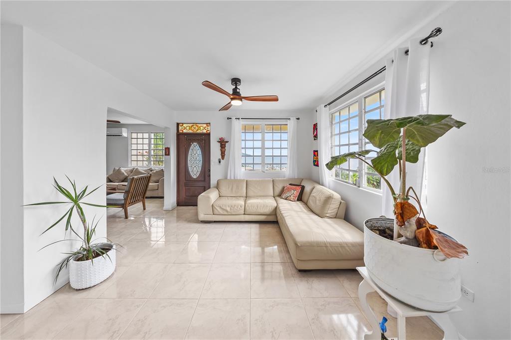A living room features light tile floors, a beige sectional sofa, and a ceiling fan — 39 BO. CAMINO NUEVO, YABUCOA, PR