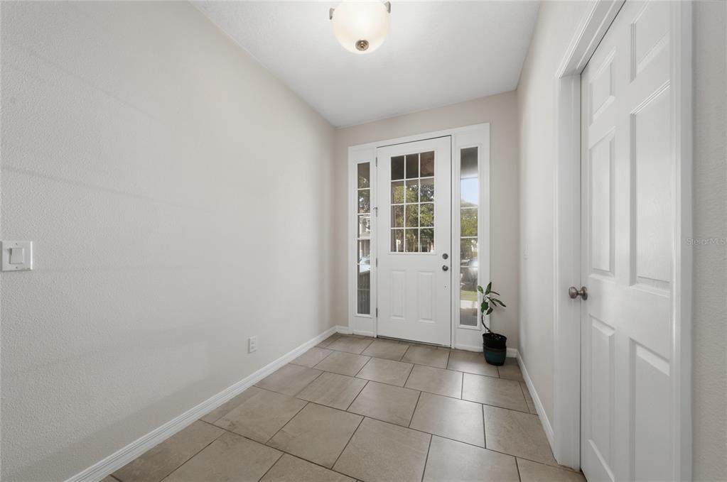 An entryway features light-colored walls, a tiled floor, a white front door, and a ceiling light — 8659 VEDDER LANE, ORLANDO, FL
