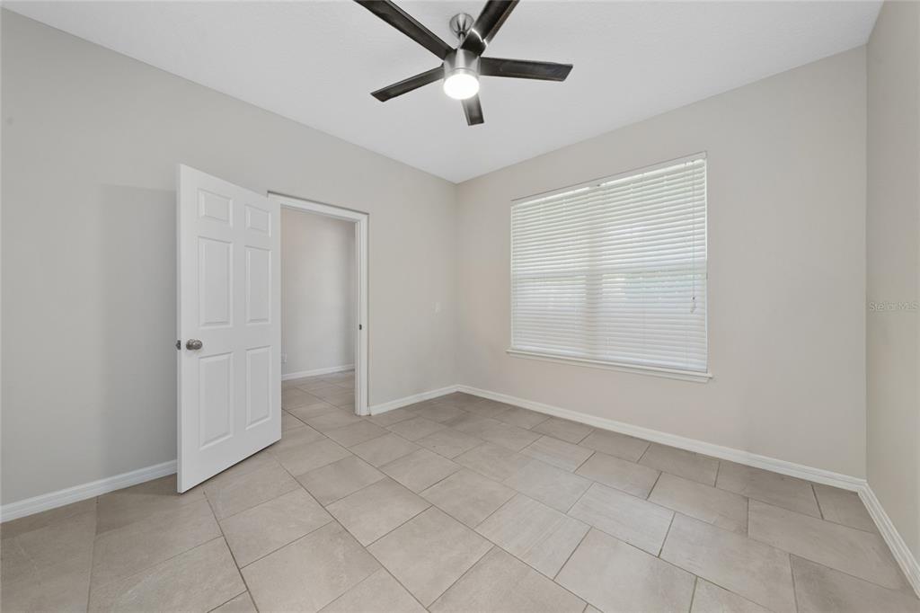 An empty bedroom features light gray walls, large beige floor tiles, and a ceiling fan — 8659 VEDDER LANE, ORLANDO, FL