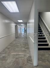 A hallway with gray tile flooring leads to a staircase with black steps and railings — 227 N MAGNOLIA AVENUE UNIT 206, ORLANDO, FL