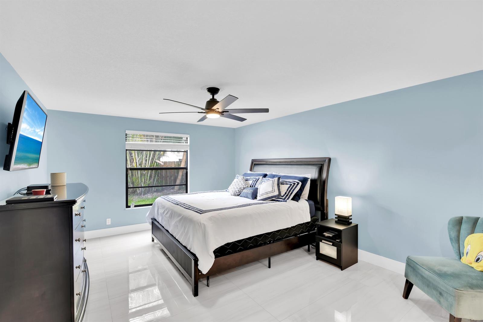 A bedroom features light blue walls, a dark wood bed frame, and white tile flooring — 8411 Theresa Road, Boynton Beach FL 33472, BOYNTON BEACH, FL
