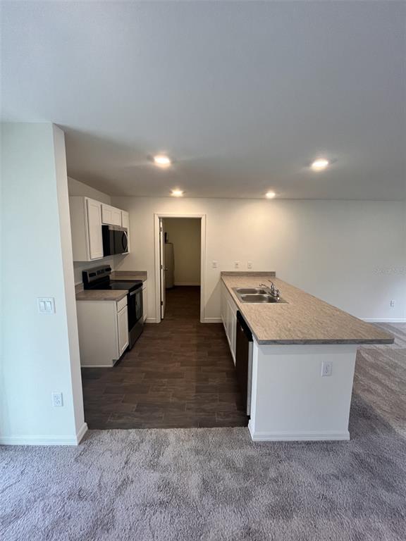 A kitchen with white cabinets, laminate countertops, and a breakfast bar overlooks a carpeted area — 10255 WEATHERBY AVENUE, HASTINGS, FL