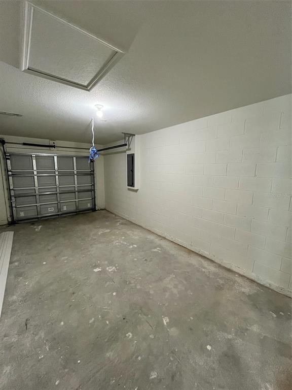 An empty garage with a concrete floor, white block walls, and a metal door — 10255 WEATHERBY AVENUE, HASTINGS, FL
