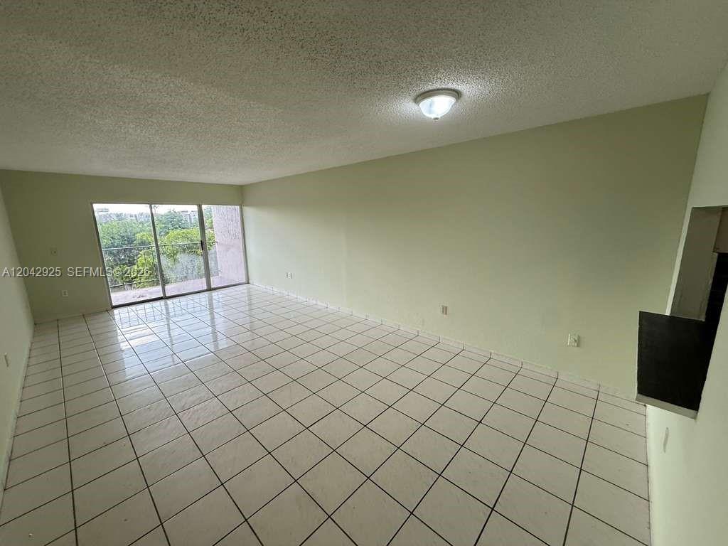 An empty room with white tile flooring, light green walls, and a sliding glass door — 1900 W 68th St # G308, Hialeah FL 33014, HIALEAH, FL