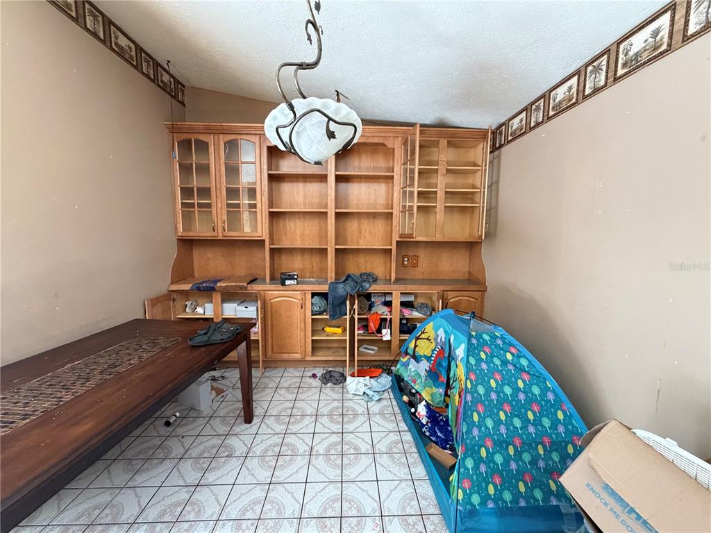 A dining room features tile flooring, a built-in wooden hutch, and a patterned wallpaper border — 14705 PENGUIN PLACE, TAMPA, FL