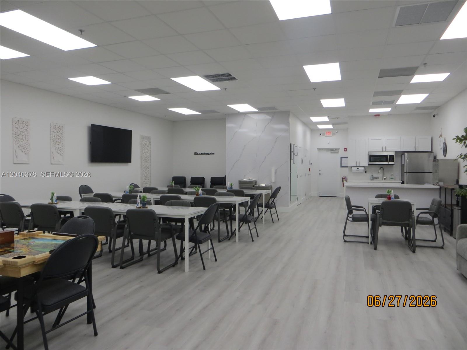 A large community room features rows of tables, chairs, a kitchenette, and light wood flooring — 4081 SW 152nd Ave, Miami FL 33185, MIAMI, FL