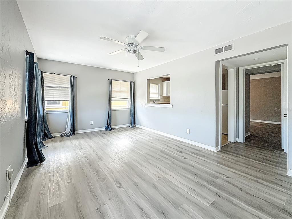A living room with light gray walls, wood-look flooring, two windows, and a ceiling fan — 107 154TH AVENUE UNIT 2, MADEIRA BEACH, FL