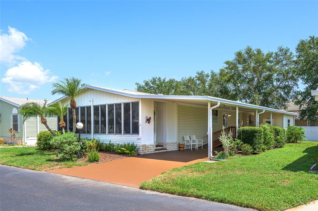 A single-story manufactured home with a screened-in porch, carport, and light green siding — 5707 45TH STREET E UNIT 222, BRADENTON, FL