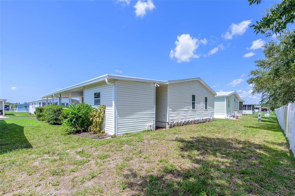 A side view of a light-colored mobile home with a carport and a grassy yard — 5707 45TH STREET E UNIT 222, BRADENTON, FL