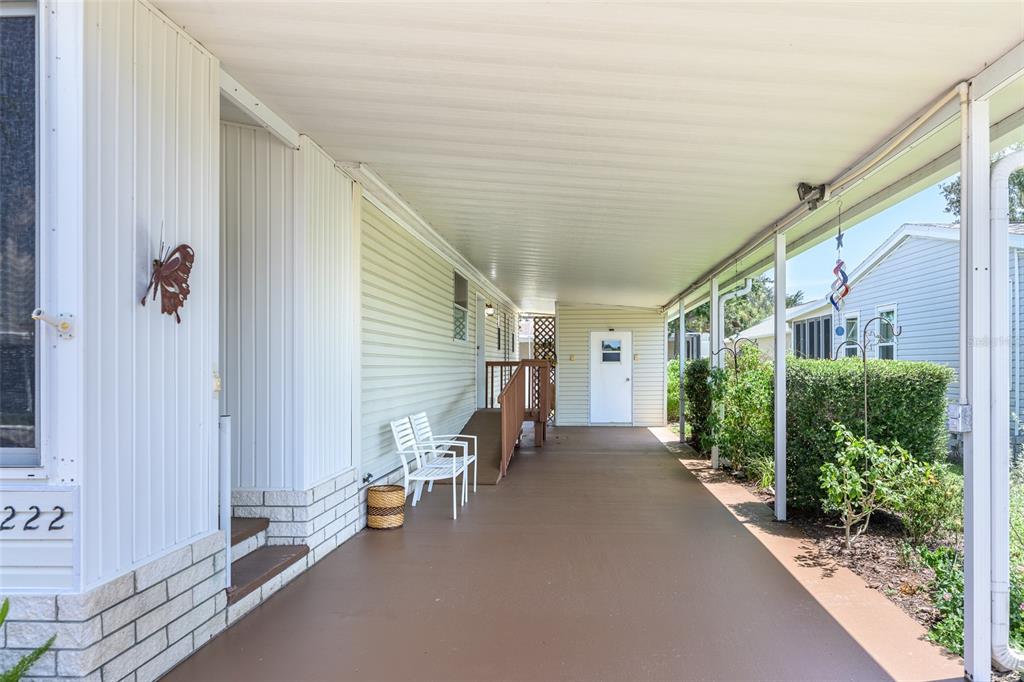 A covered carport with a concrete floor, white siding, and a wooden wheelchair ramp — 5707 45TH STREET E UNIT 222, BRADENTON, FL