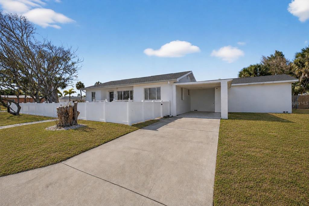 A white single-story house features a concrete driveway, a carport, and a white privacy fence — 292 42ND AVENUE, ST PETE BEACH, FL