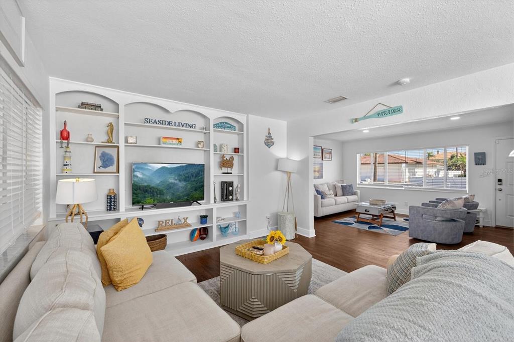 A living room features a white built-in entertainment center, light-colored sofas, and hardwood flooring — 292 42ND AVENUE, ST PETE BEACH, FL