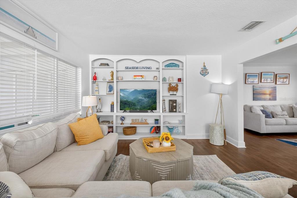 A living room features a white built-in entertainment center, a sectional sofa, and wood flooring — 292 42ND AVENUE, ST PETE BEACH, FL