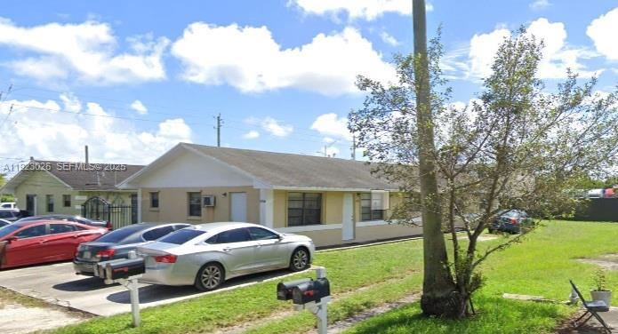 A single-story residential building with a light-colored exterior sits beside a grassy yard — 2416 NW 79th Ter, Miami FL 33147, MIAMI, FL