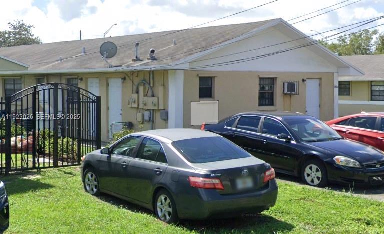 A single-story building with a beige exterior and two cars parked in the front yard — 2416 NW 79th Ter, Miami FL 33147, MIAMI, FL
