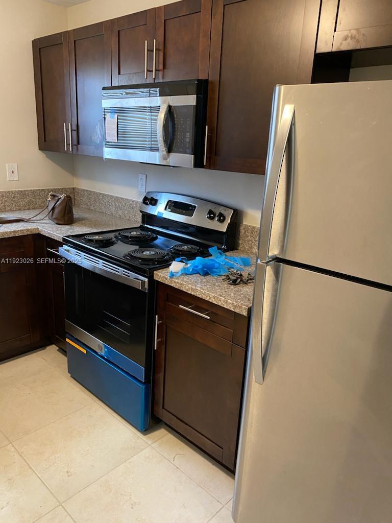 A kitchen features dark wood cabinets, stainless steel appliances, and speckled granite countertops — 2416 NW 79th Ter, Miami FL 33147, MIAMI, FL