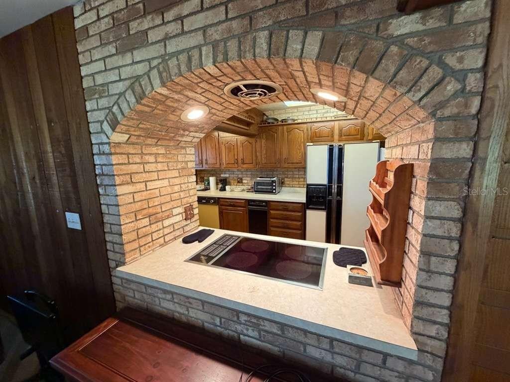 A kitchen features a brick archway over a countertop with a built-in electric cooktop — 930 SHORE DRIVE, KISSIMMEE, FL