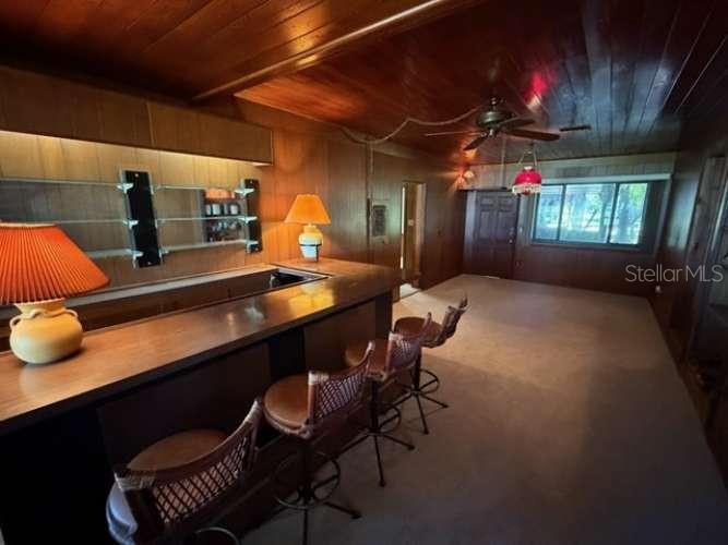 A dining area with a wooden table, chairs, brick walls, and a view into the kitchen — 930 SHORE DRIVE, KISSIMMEE, FL