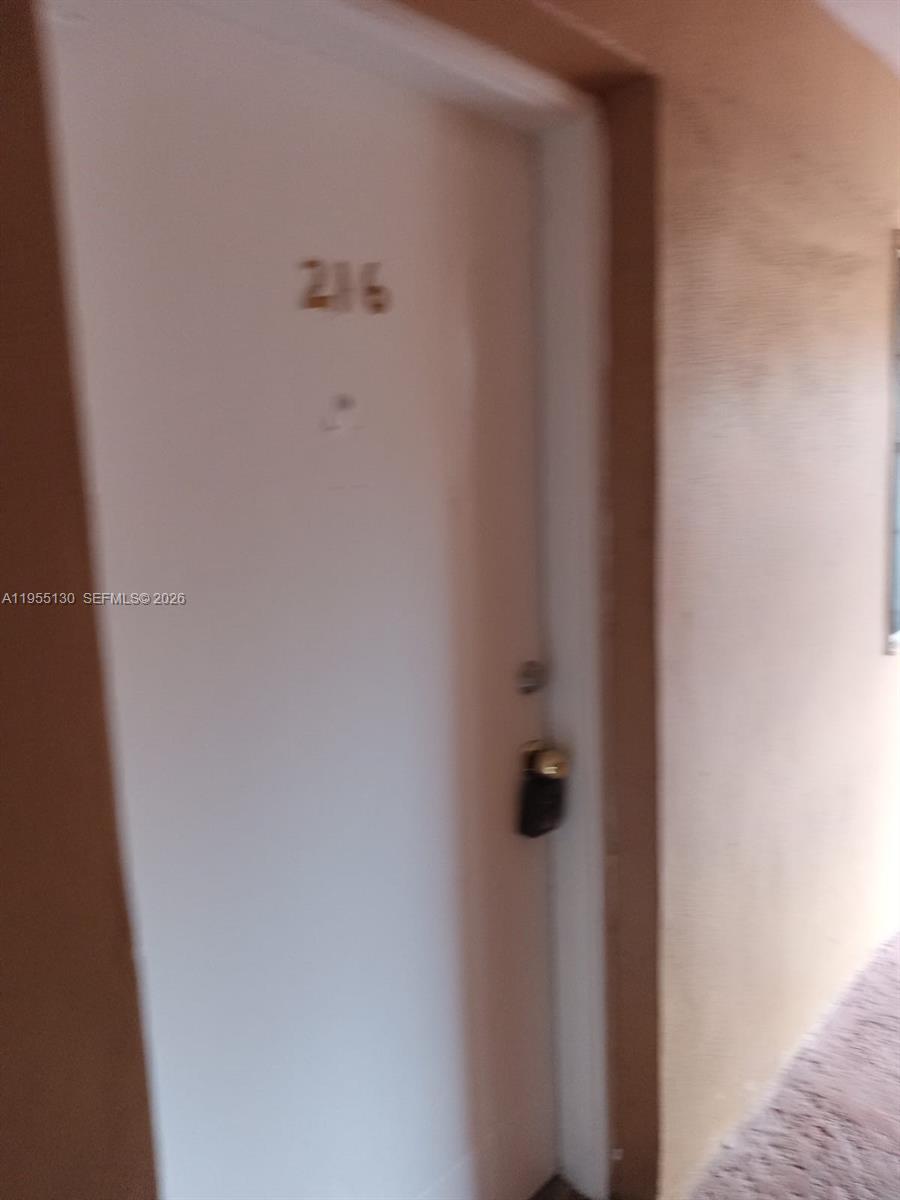 A white apartment door labeled 216 features a black lockbox attached to the handle — 1230 W 54th St # 216A, Hialeah FL 33012, HIALEAH, FL