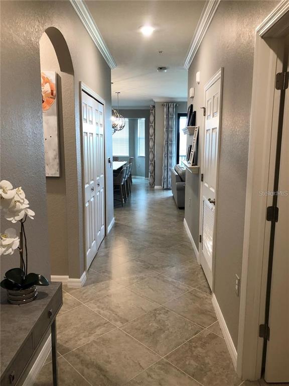 A tiled hallway leads from a foyer past white doors toward a living area — 17510 GAWTHROP DRIVE UNIT 405, LAKEWOOD RANCH, FL