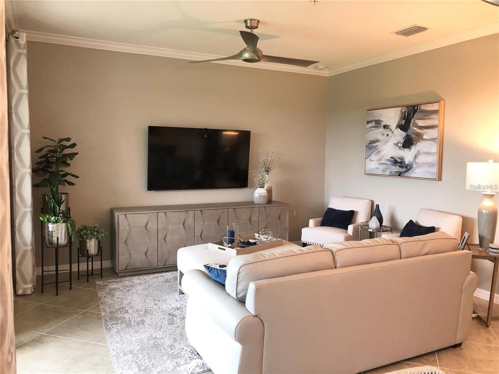 A living room features a wall-mounted television, a long console table, and a neutral sofa — 17510 GAWTHROP DRIVE UNIT 405, LAKEWOOD RANCH, FL