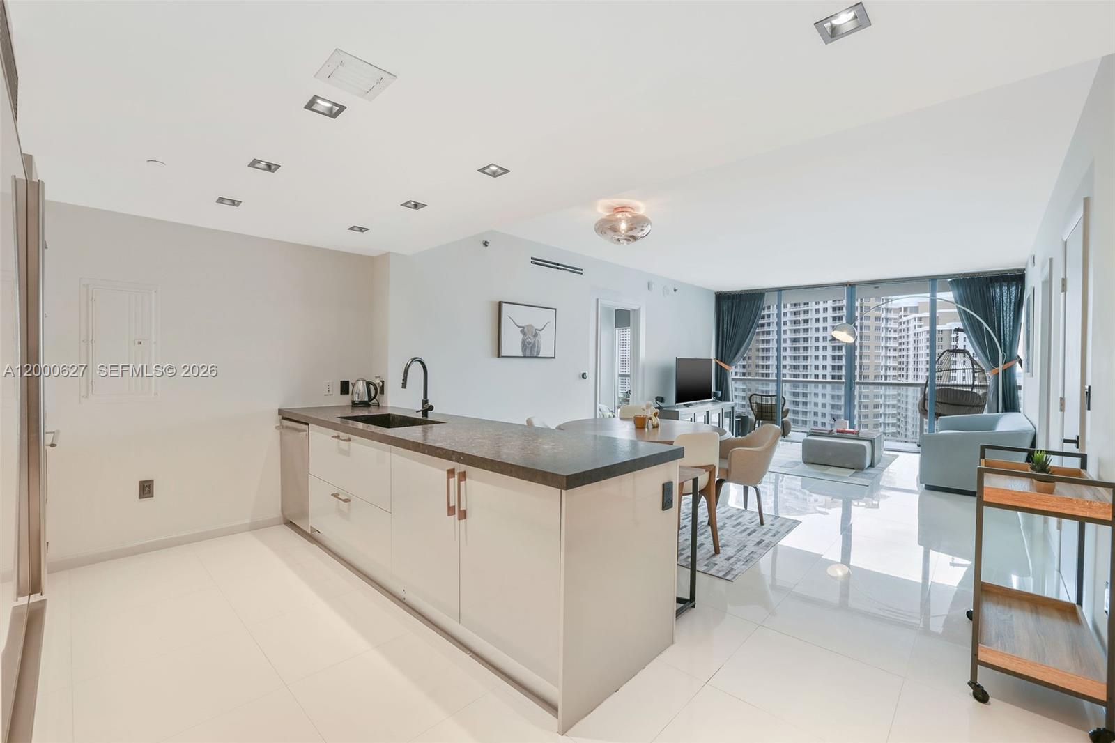 A modern open-concept kitchen and living area features white tile floors and floor-to-ceiling windows — 465 Brickell Ave # 1805, Miami FL 33131, MIAMI, FL