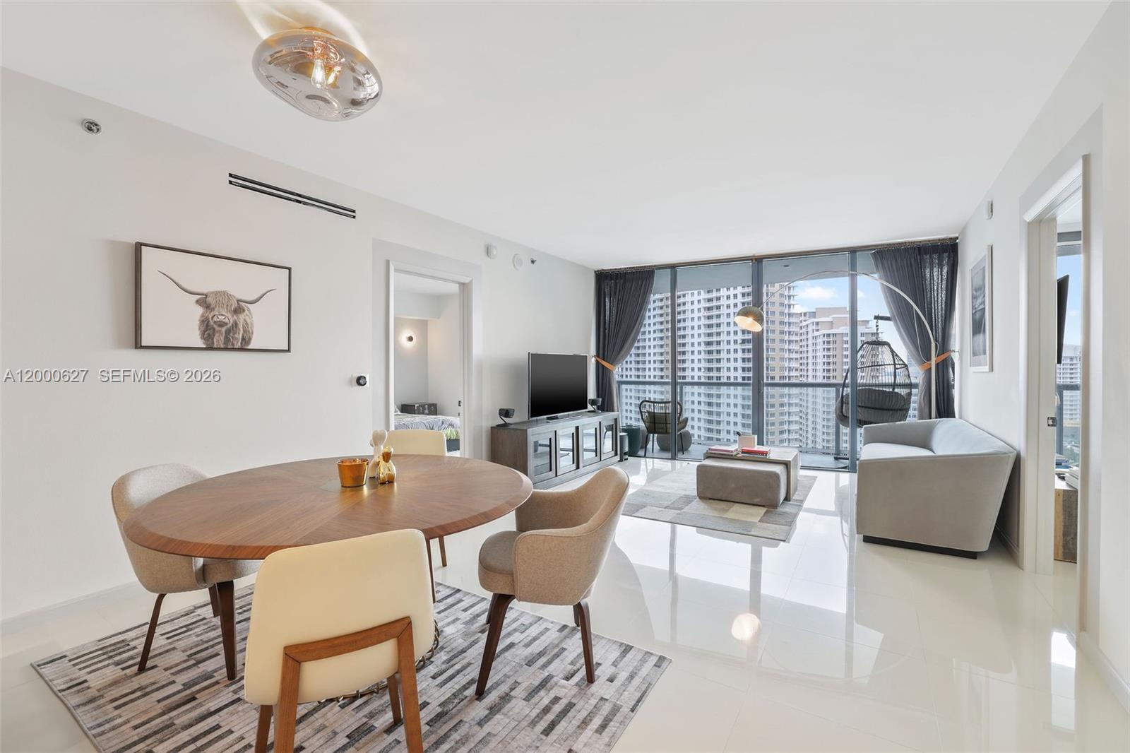 A modern living and dining area features floor-to-ceiling windows with city views and tile flooring — 465 Brickell Ave # 1805, Miami FL 33131, MIAMI, FL