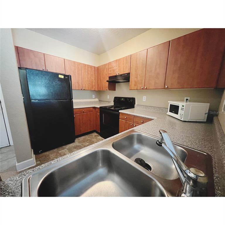 A kitchen features wood cabinets, black appliances, a double-basin sink, and speckled laminate countertops — 304 E SOUTH STREET UNIT 3019, ORLANDO, FL
