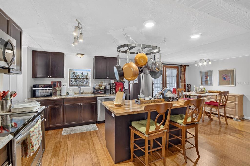 A kitchen features dark wood cabinets, a butcher block island, and a hanging pot rack — 2715 EATON AVENUE, EATON PARK, FL