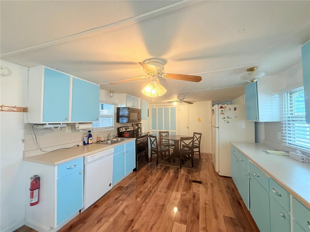 A kitchen with light blue cabinets, wood-look flooring, a dining area, and white appliances — 38645 REMORA AVENUE, ZEPHYRHILLS, FL