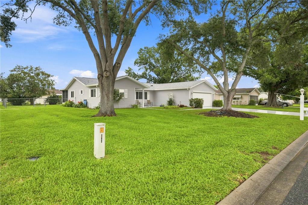 A single-story light gray house with a garage and large trees on a grassy lawn — 10435 SE 178TH PLACE, SUMMERFIELD, FL