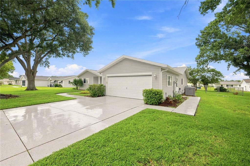 A light gray house with a single-car garage, concrete driveway, and green lawn — 10435 SE 178TH PLACE, SUMMERFIELD, FL