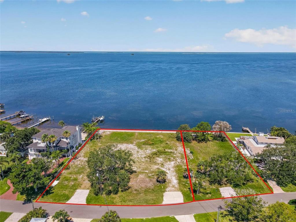 An aerial view shows two adjacent waterfront lots with grass and trees along a bay — MAYO STREET, PALM HARBOR, FL