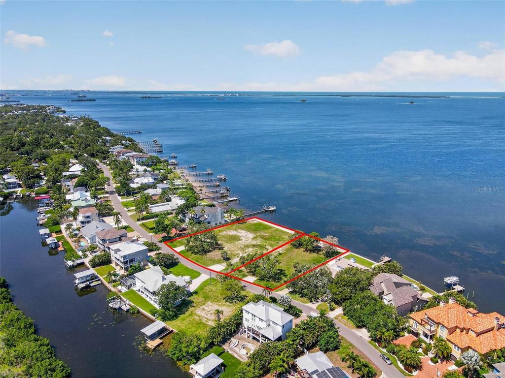 An aerial view shows two adjacent vacant waterfront lots outlined in red along a bay — MAYO STREET, PALM HARBOR, FL