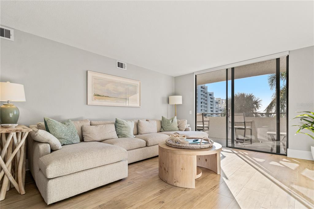 A living room features a beige sectional sofa, a round wooden coffee table, and a balcony — 6035 SEA RANCH DRIVE UNIT 203, HUDSON, FL