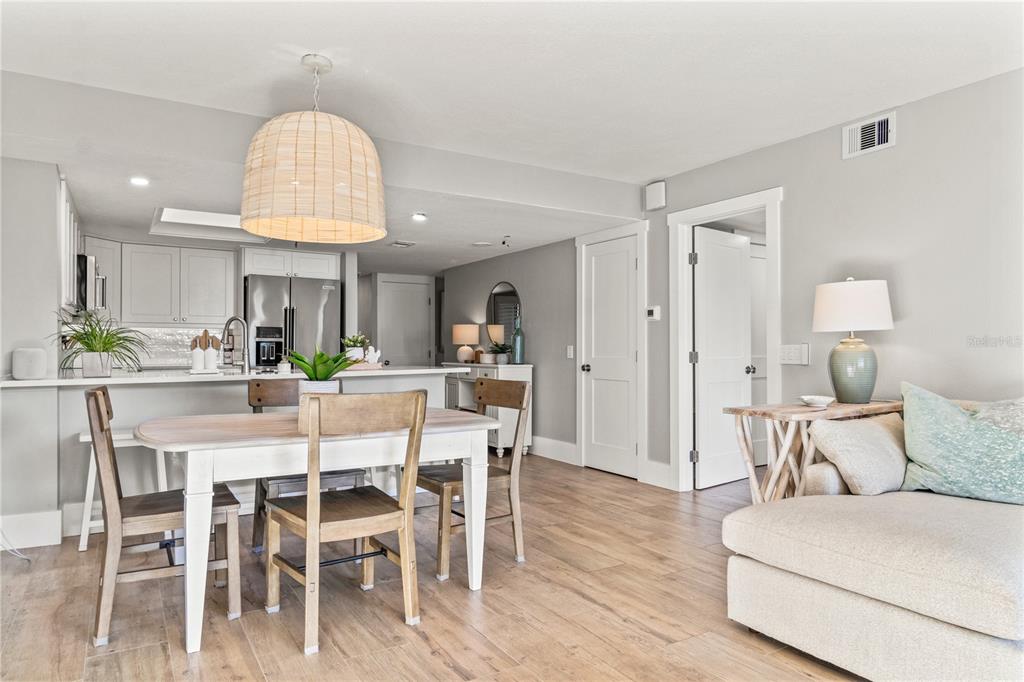 A dining area with a wooden table and chairs sits adjacent to a modern kitchen — 6035 SEA RANCH DRIVE UNIT 203, HUDSON, FL