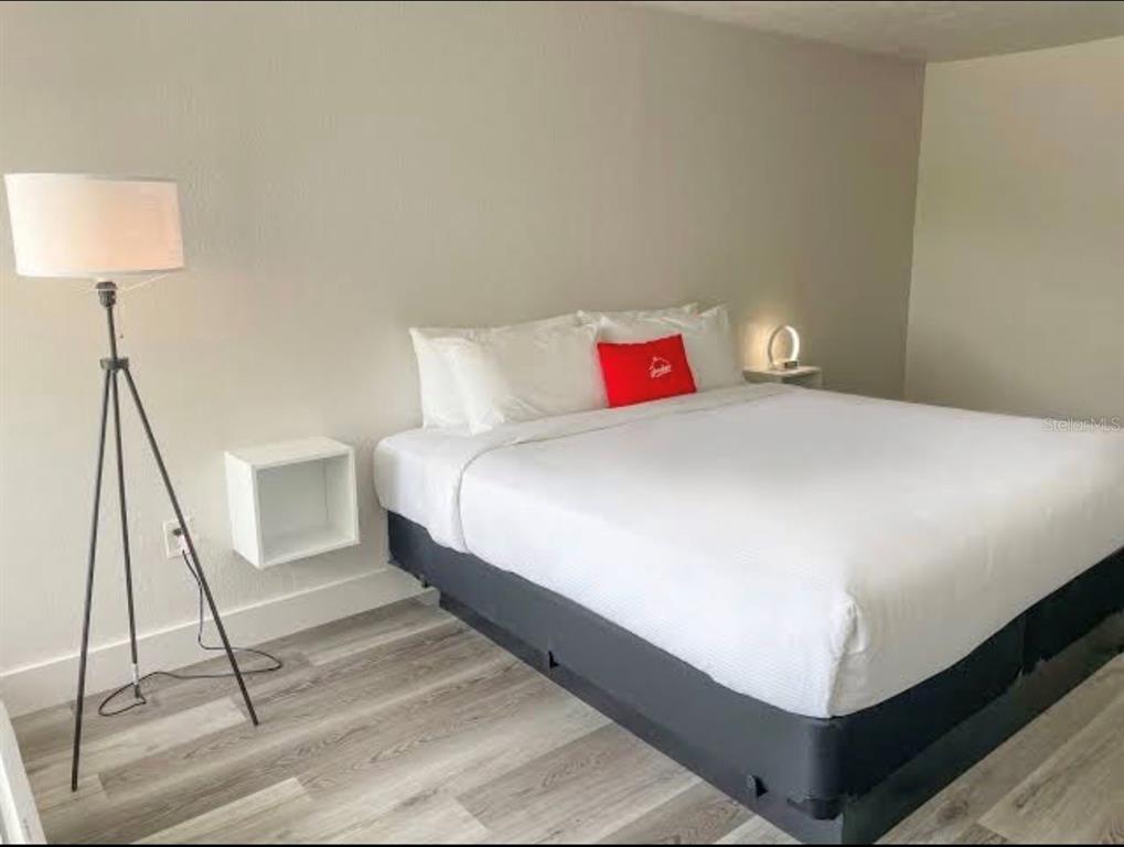 A bedroom features a bed with white linens, a red accent pillow, and a floor lamp — 2930 POLYNESIAN ISLE BOULEVARD UNIT 221, KISSIMMEE, FL