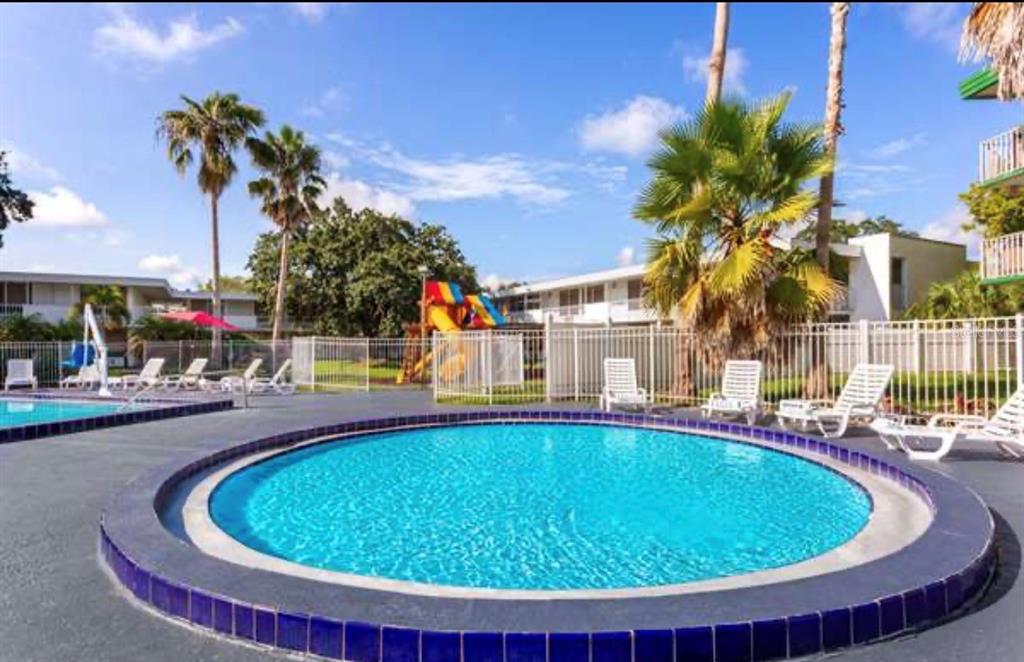 A circular swimming pool sits on a patio with lounge chairs and a playground nearby — 2930 POLYNESIAN ISLE BOULEVARD UNIT 221, KISSIMMEE, FL