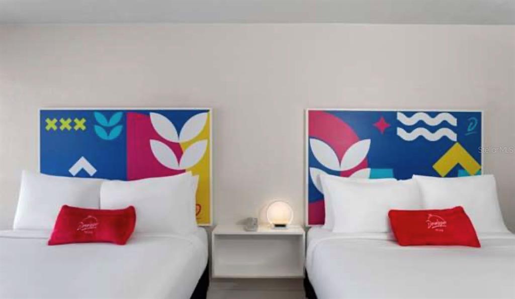 A bedroom features two beds with white linens, red accent pillows, and colorful abstract headboards — 2930 POLYNESIAN ISLE BOULEVARD UNIT 221, KISSIMMEE, FL